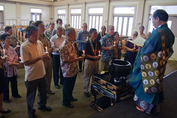 Rev. Muneto stands before the 2014-2015 directors, who are holding candles