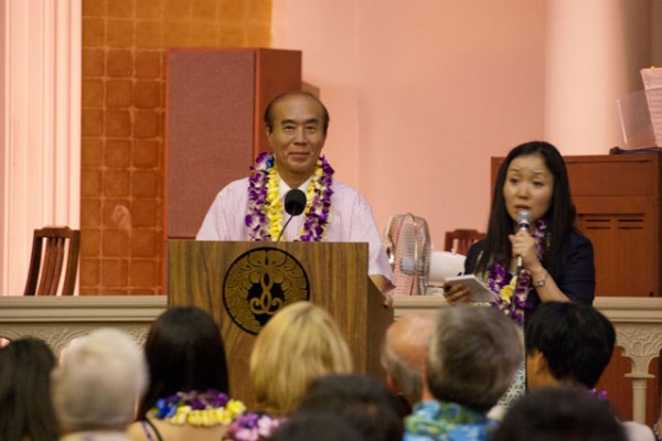 Masahiro Sasaki, brother of Sadako Sasaki, at the podium in the hondo with his translator