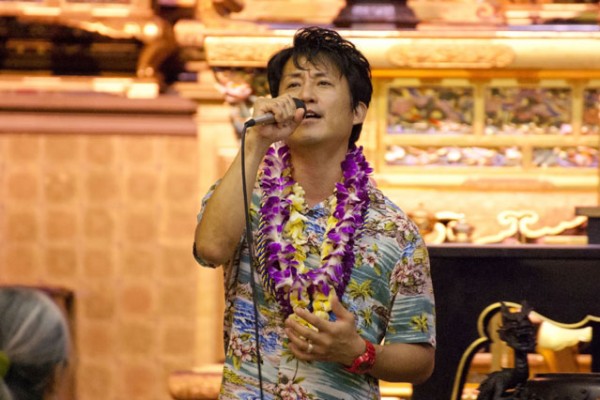 Yuji Sasaki, wearing lei, sings in the hondo