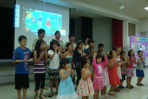 children dance at the front of the social hall with projected animation in the background