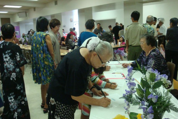 people at entry way tables writing notes of appreciation to Mrs. Saito