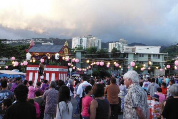 Looking over the parking lot with crowds, yagura, and glowing clouds in the background