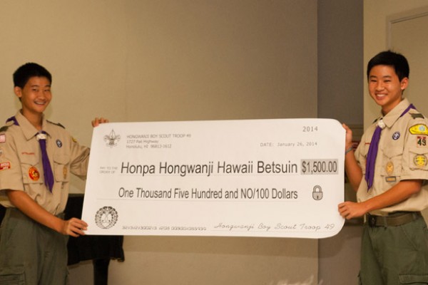 Two Troop 49 Boy Scouts hold up an oversized check in the amount of $1500, presented to the Hawaii Betsuin.