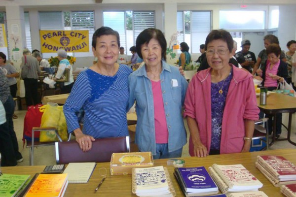 three members at a table with cookbooks displayed