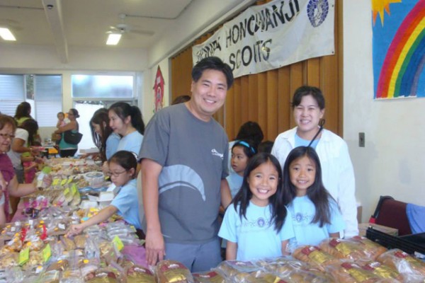 parents and girls behind the bake sale table