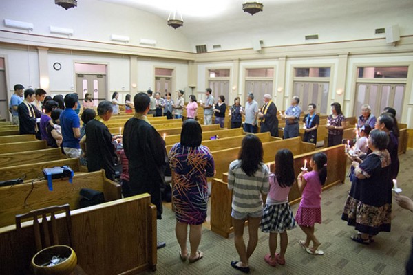 sangha members form a circle around the pews and hold candles