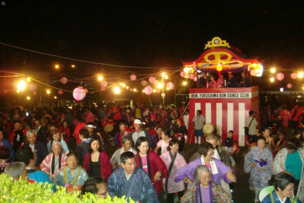 crowd of dancers face the camera with the yagura in the background