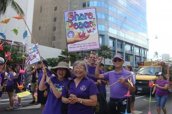 purple-shirted parade participants with Share Peace signs and