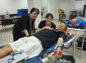 man on stretcher giving blood with two female attendants