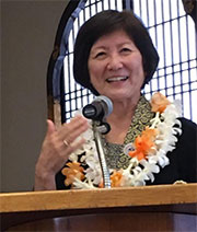 Barbara Brennan with lei at podium