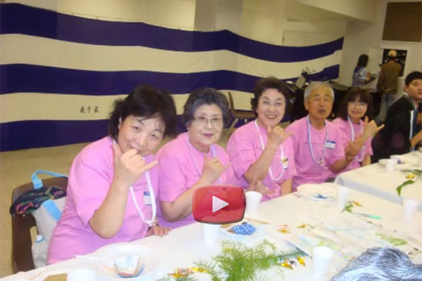 members of the Aki choir from Hiroshima at a table; video play button overlay