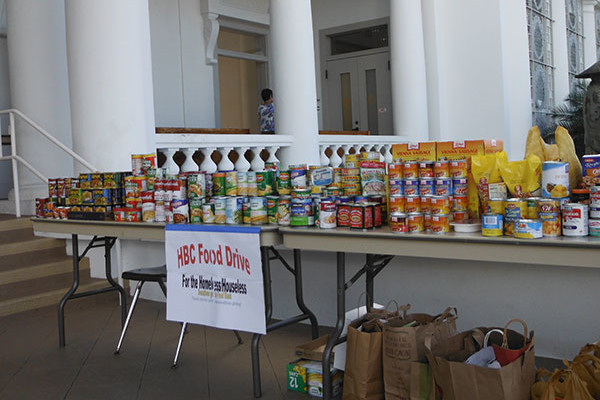 tables with cans of food stacked on top and bags of food underneath outside the main temple hall