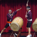 Close up of Alan Kubota and youth member playing taiko drums