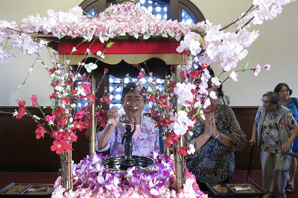 pouring sweet tea over the statue of baby Buddha at the HBC 2017 Buddha Day service