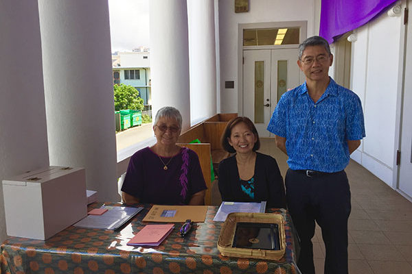 three smiling greeters at the registration table