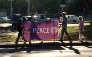 carrying the Imagine Peace banner; silhouette of a minister's robes on backlit banner