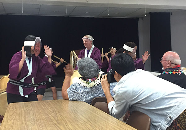 Ms. Takenaka and Rev. Arthur Kaufmann are entertained by taiko drumming in the Social Hall, including some drummers wearing masks of the honorees