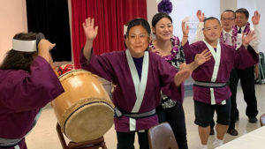 Betsuin Ministers dancing with the beat of Dharma School Taiko wearing masks of the ministers' faces