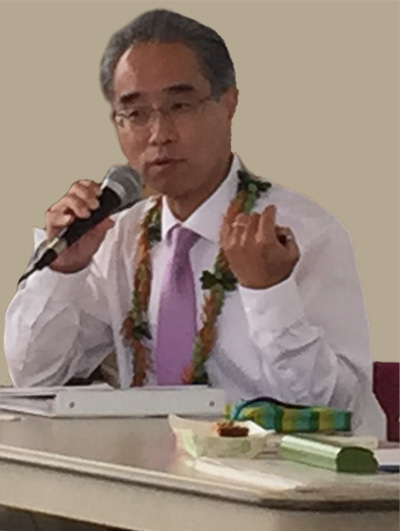 A seated Bishop Eric Matsumoto speaks in the Annex Temple