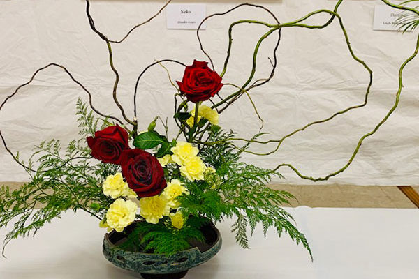 Jane Hamaji's flower arrangement of red roses, ferns, and carnations.