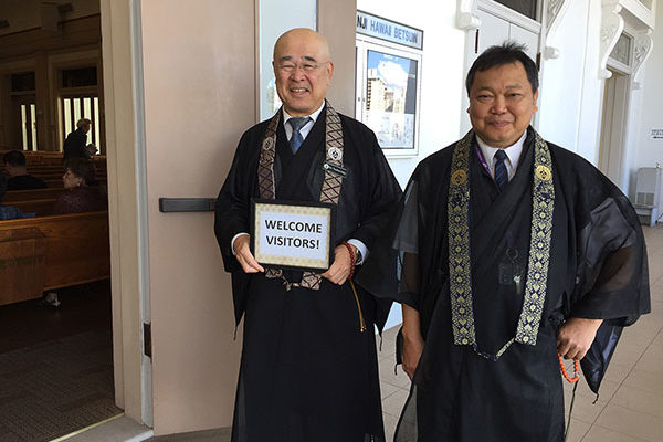 Rimban Hagio and Rev. Sol Kalu hold a "Welcome Visitors" sign at the hondo entrance on March 3, 2019