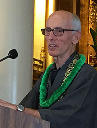Roshi Michael Kieran at the podium, wearing a green lei, at the Earth Day Service 2019