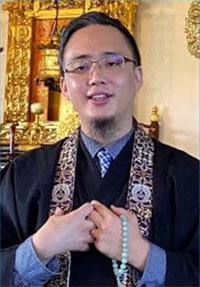 Rev. Satoshi Tomioka, smiling, in robes at altar