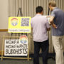 Jon Matsuoka (Hawai‘i Betsuin) and Joe Wilson (Pua ʻAla Queer Histories of Hawai‘i) look at signs before the event. A couple of the signs had been carried by the Hongwanji group in the recent Honolulu Pride Parade. (Kagirinaki Ai to Jihi, 10/25/24)